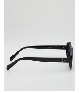 Detail view of oval sunglasses featuring black acetate frame with three gold cross rivets
