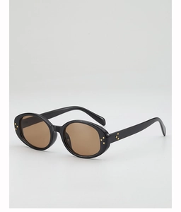 Detail view of oval sunglasses with gold cross rivets and brown lenses for UV protection