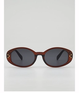 Detail of oval sunglasses with brown translucent frames and gold cross rivet accents