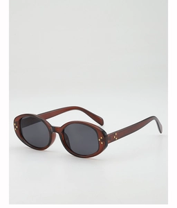 Close-up of translucent coffee oval frames with gold cross rivets and dark UV lenses