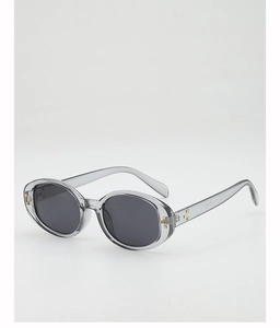 Detail view of oval sunglasses with transparent grey frame and gold rivet accents