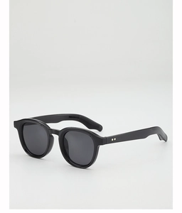Close-up of retro round black frames with dark grey lenses and gold dot accents