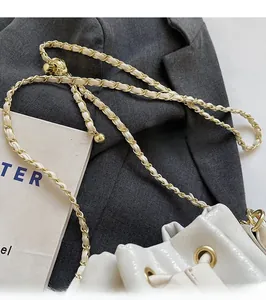 Detail of glossy white bucket bag with a golden chain and leather interwoven strap