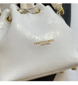 Detail of white bucket bag featuring pearlescent cracked leather and gold hardware