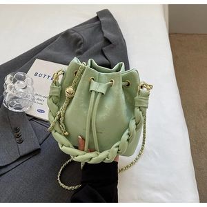 Detail of mint green bucket bag with drawstring closure and golden chain strap