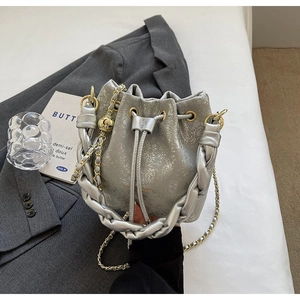 Close-up of silver bucket bag with cracked metallic texture and woven handle