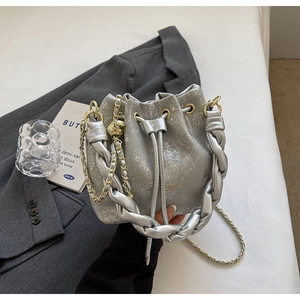 Detail of silver bucket bag with cracked texture, woven handle and gold ball chain