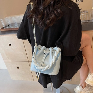 Pale blue glossy bucket bag with woven handle and gold chain strap shown on model