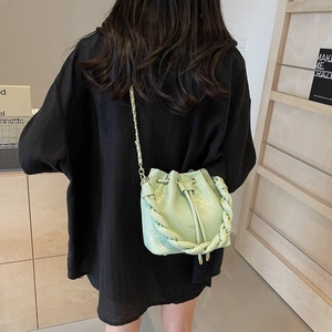 Detail of mint green mini bucket bag with woven handle and drawstring closure on shoulder