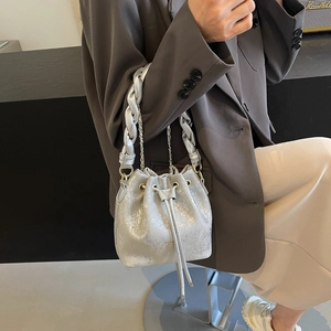 Detail of silver metallic bucket bag featuring drawstring closure and woven handle