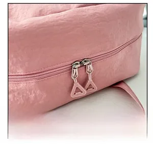 Dettaglio delle doppie cerniere rosa e tiranti a triangolo di una borsa in tela