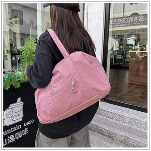 Dettaglio borsa a tracolla in nylon rosa con cerniera e ampia tracolla sulla modella