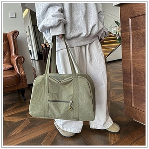 Dettaglio borsa da viaggio in tela verde oliva con tasca a zip e spallacci lunghi