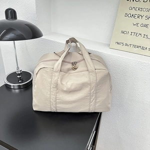 Dettaglio della borsa da viaggio in nylon beige con trama resistente e ampi manici