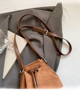 Close-up of brown suede bucket bag featuring drawstring closure and adjustable silver buckle