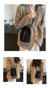 Detail of minimalist black drawstring bucket bag worn with a beige blazer in a cafe