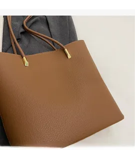 Close-up of brown pebbled leather bucket bag with golden metal hardware detail