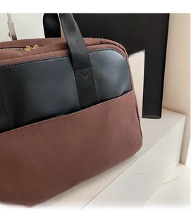 Detail shot of brown canvas and black leather stitching on a large tote bag