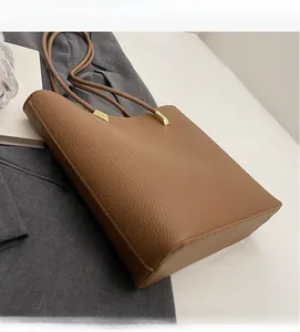 Detail of caramel brown lychee grain leather tote bag with gold metal buckle accents