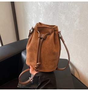 Detailed macro of brown suede bucket bag texture with leather drawstring and silver hardware