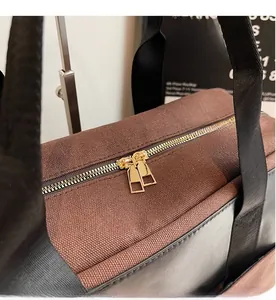 Detail of smooth gold dual metal zippers on a brown canvas tote bag for women