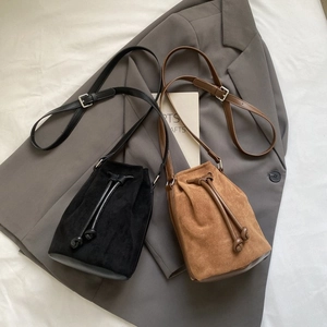 Top view of bucket bags in black and caramel suede with drawstring and strap detail