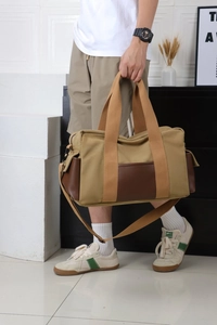 Détail du sac de voyage en toile kaki et cuir marron avec bandoulière réglable