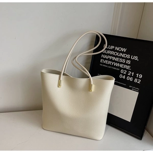 Detail of cream tote bag with pebble leather texture and gold metal hardware