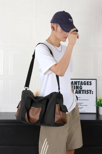 Détail d'un sac en toile noire avec finitions cuir marron et bandoulière en nylon robuste