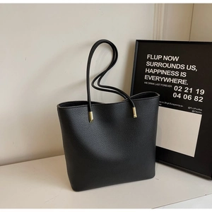 Detail of black pebbled leather tote bag with elegant gold hardware and thin straps