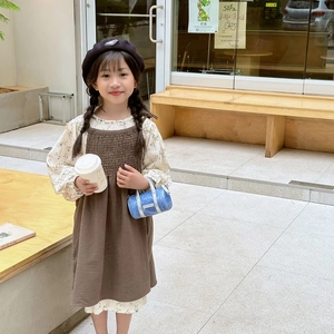 Close-up of girls' autumn floral shirt and brown pleated cotton dress with ruffles