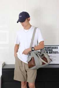 Détail d'un sac de voyage en toile gris-vert avec des touches de cuir sur un mannequin