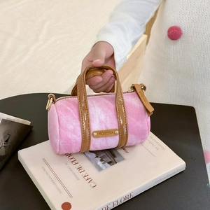 Detailed close-up of a mini pink denim cylinder handbag with brown leather trim and metal tag