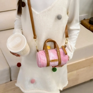 Pink velvet cylinder bag worn over the shoulder, featuring KOYOKA logo and gold hardware