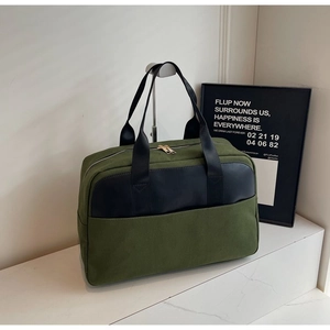 Detail of olive green canvas travel bag with black leather trim and gold zippers