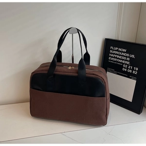 Close-up of vintage brown canvas handbag with black leather pocket and golden zipper detail
