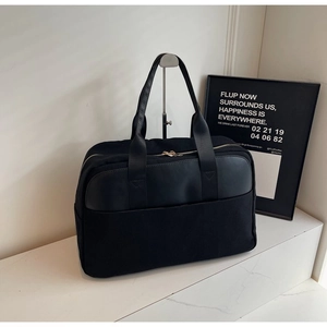Detailed shot of large black tote bag featuring canvas and leather stitching on display