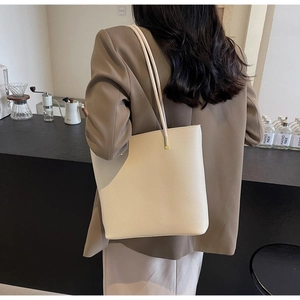 Beige lychee leather tote bag with gold hardware shown in a modern cafe setting