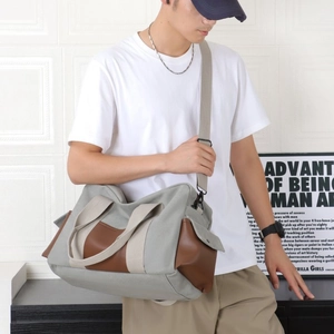 Détails d'un grand sac de voyage en toile grise et cuir porté par un mannequin