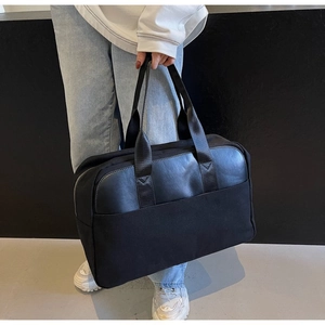 Detail of a black large-capacity canvas travel bag with leather patchwork and handles