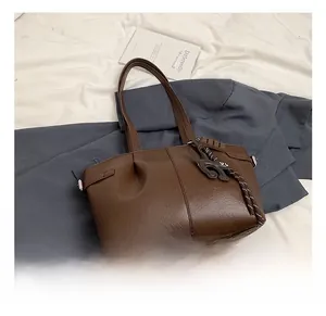 Detail of dark brown pebble leather tote bag with shoulder strap and animal charm