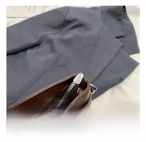 Detail of silver metal zipper and precise stitching on dark brown leather tote bag