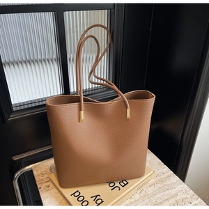 Detail of caramel lychee grain leather tote bag with gold hardware on book