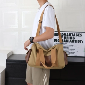 Détail d'un grand sac de voyage en toile avec finitions en cuir brun et bandoulière