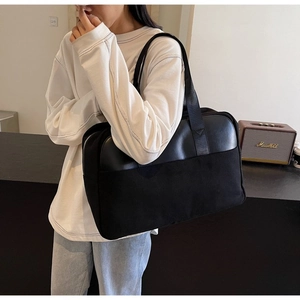 Detail of a black large capacity tote bag with canvas and leather stitching on model