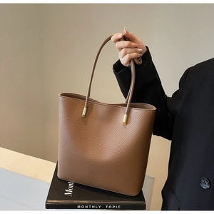 Close-up of caramel lychee pattern leather tote bag with gold metal hardware details