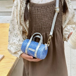 Close-up of blue denim cylinder bag with silver metal handle and KOYOKA nameplate