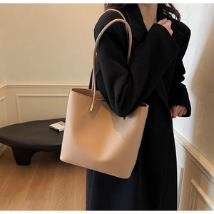 Detail of apricot bucket bag with grainy texture and gold metal hardware on the strap