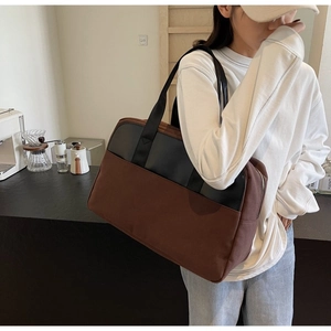 Detail view of large canvas tote bag with brown patchwork and black leather shoulder strap
