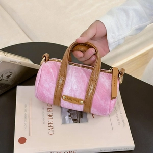 Detail of pink denim barrel bag with brown leather trim and golden metal logo